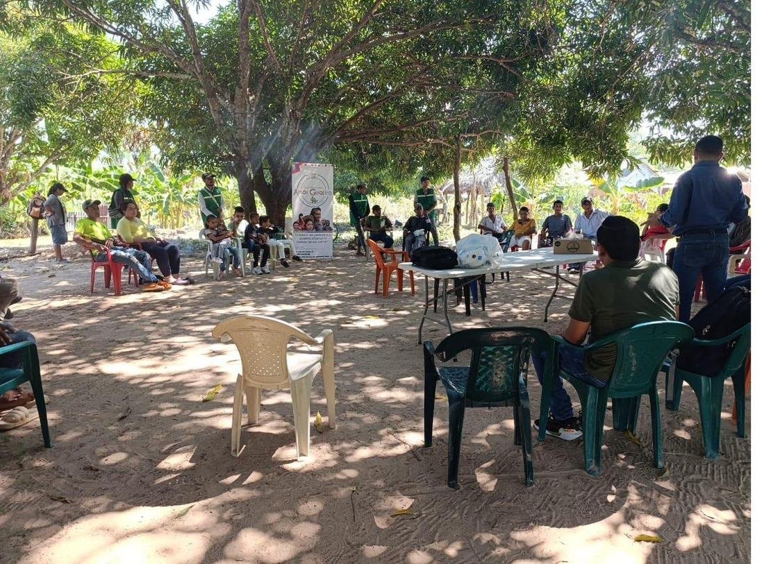 Asamblea comunitaria sentada en círculo bajo los árboles durante una jornada de la Fundación